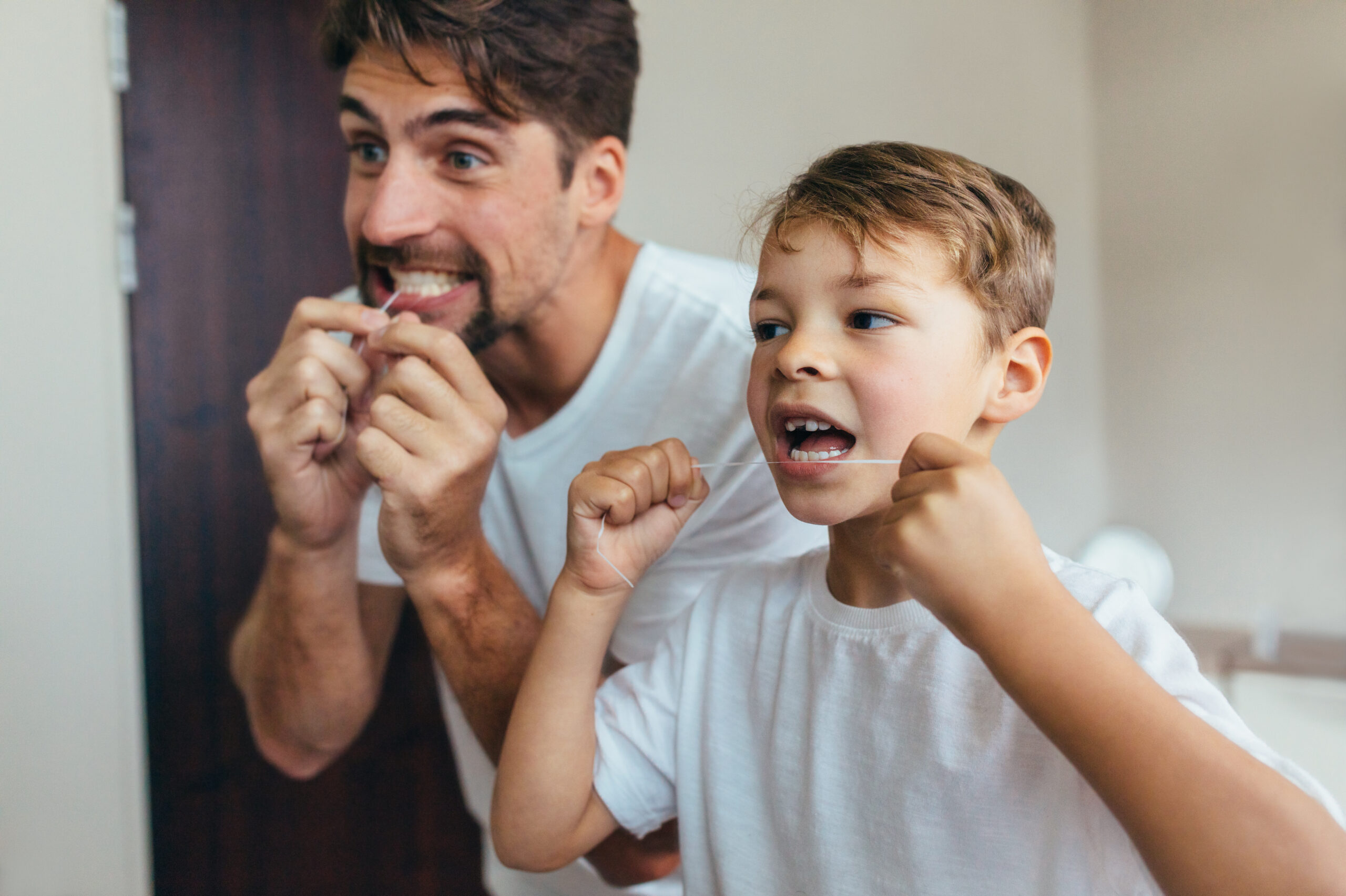 Father and son floss their teeth together
