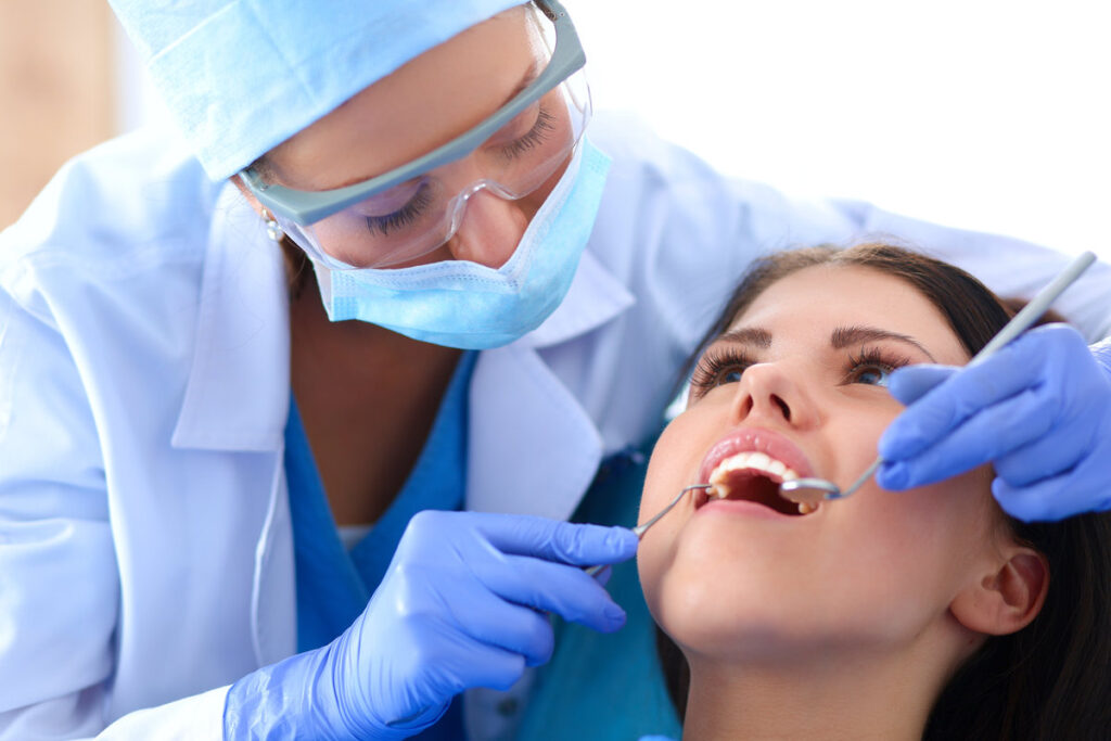 Woman dentist working at her patients teeth .