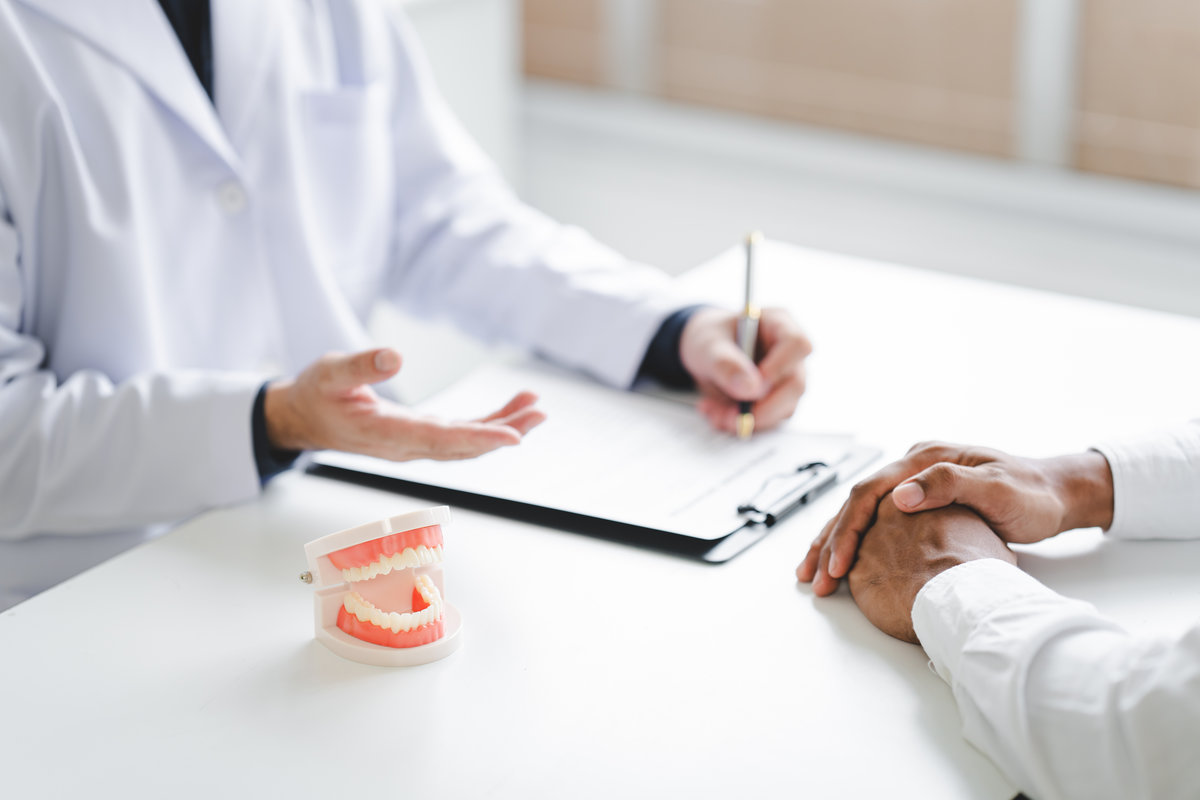 Dentist explaining endodontic treatment to patient in office Dentist holding a tooth model for examination and research